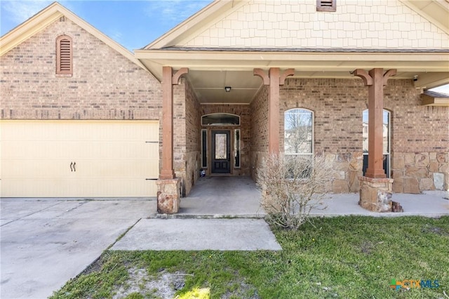 property entrance featuring an attached garage, concrete driveway, and brick siding