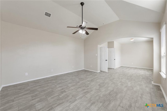 spare room featuring baseboards, visible vents, arched walkways, a ceiling fan, and lofted ceiling