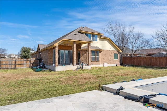 back of house with a yard, a fenced backyard, a patio area, and brick siding