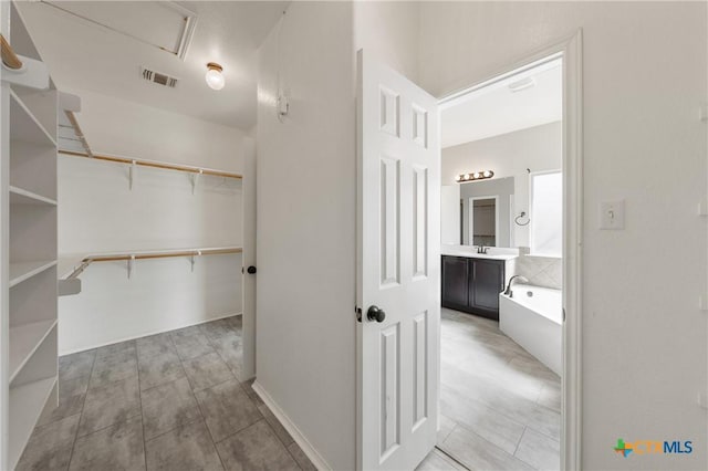 spacious closet with visible vents and a sink