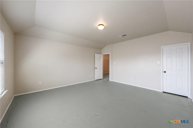 spare room featuring finished concrete floors, a healthy amount of sunlight, visible vents, and vaulted ceiling