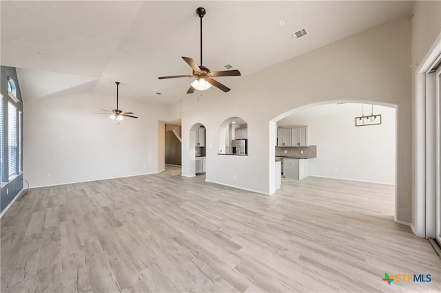 unfurnished living room featuring light wood-type flooring, arched walkways, visible vents, and a ceiling fan