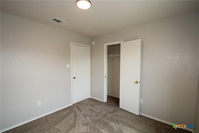 unfurnished bedroom with baseboards, carpet, a closet, and visible vents
