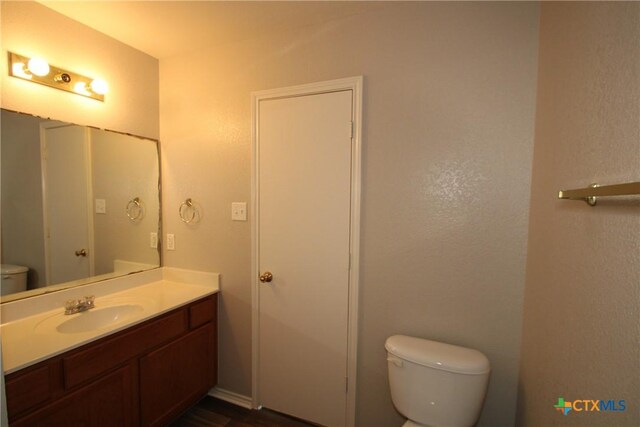 bathroom featuring toilet, wood finished floors, and vanity