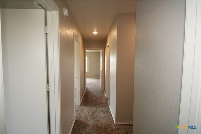 corridor with carpet floors, a textured wall, baseboards, and recessed lighting