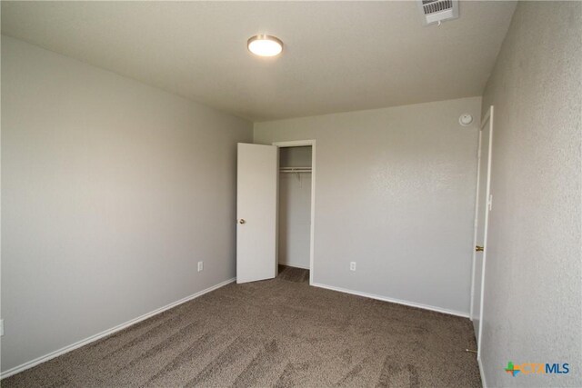 unfurnished bedroom featuring visible vents, baseboards, carpet floors, and a closet