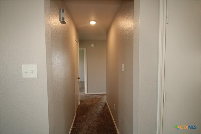 hallway with baseboards, carpet, and a textured wall