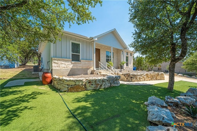 view of front facade featuring central AC unit, board and batten siding, and a front yard