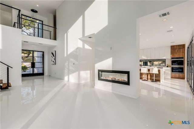 unfurnished living room featuring light tile patterned floors and a high ceiling