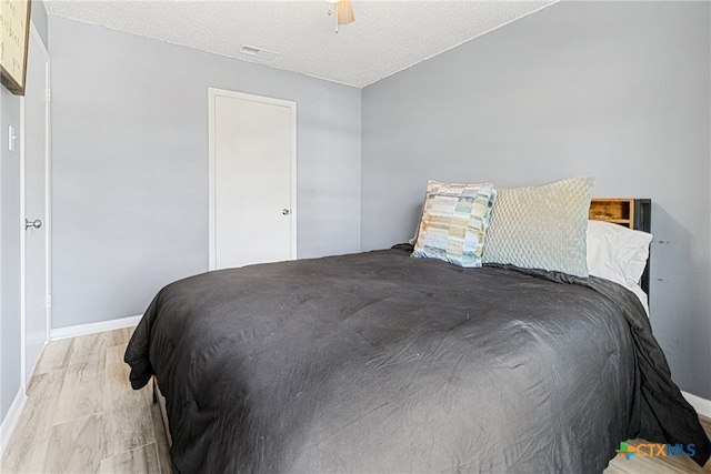 bedroom featuring a textured ceiling, light hardwood / wood-style flooring, and ceiling fan