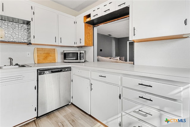 kitchen featuring stainless steel appliances, a textured ceiling, sink, white cabinetry, and light hardwood / wood-style flooring