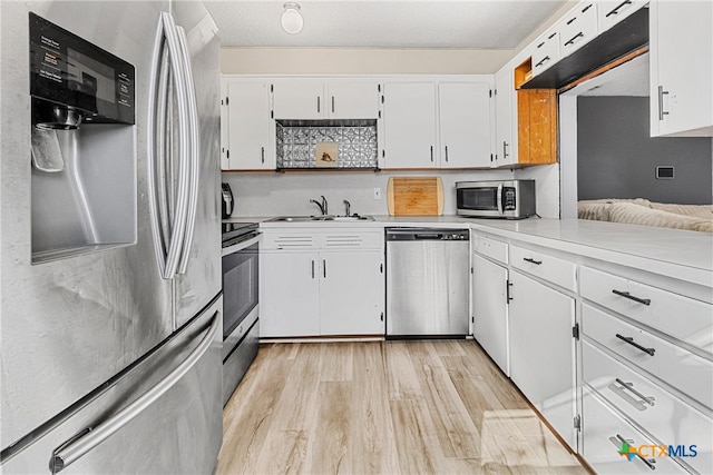 kitchen with white cabinetry, stainless steel appliances, sink, and light hardwood / wood-style flooring