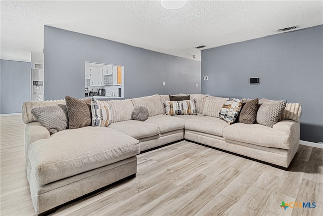 living room featuring a textured ceiling and light hardwood / wood-style flooring