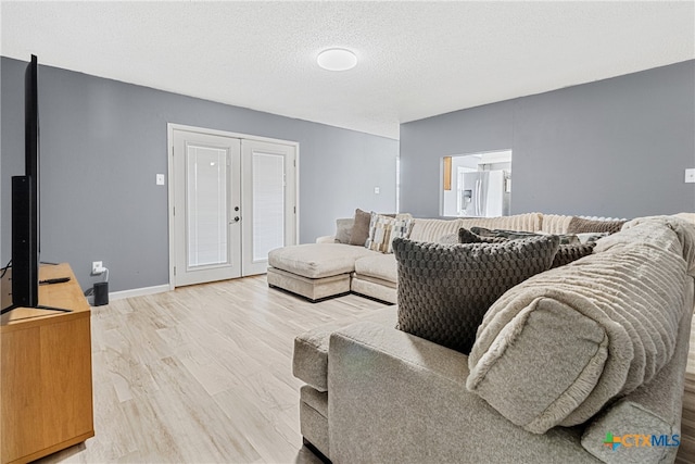 living room with a textured ceiling, french doors, and hardwood / wood-style flooring