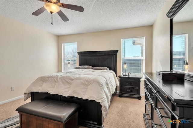 bedroom with ceiling fan, light colored carpet, and a textured ceiling