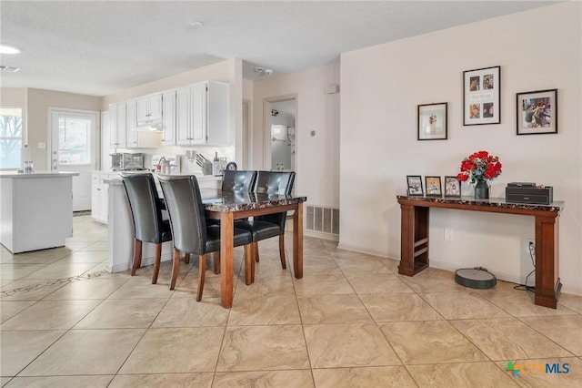 dining area featuring light tile patterned flooring and a textured ceiling