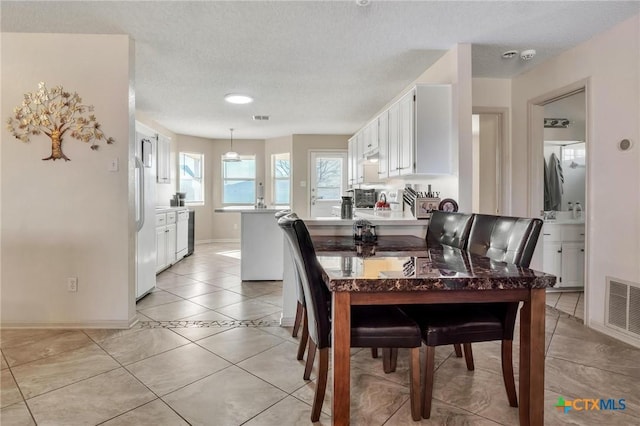 dining area featuring light tile patterned floors and a textured ceiling