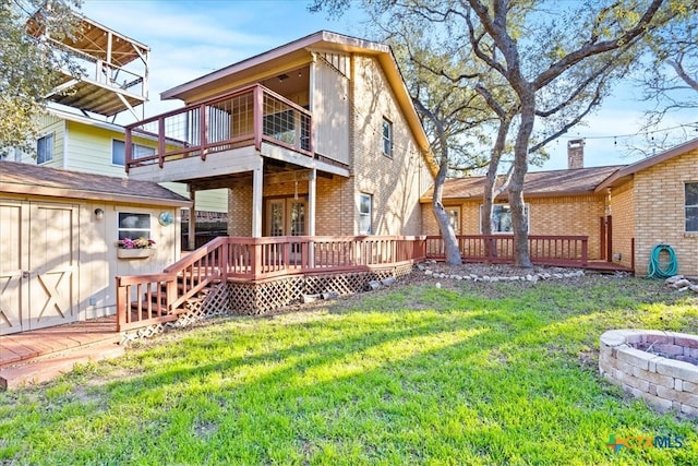 rear view of property featuring a yard, an outbuilding, a deck, and brick siding