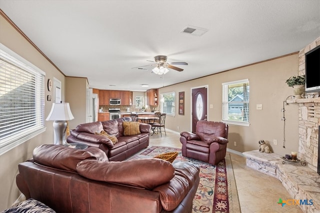 living area with crown molding, a fireplace, visible vents, and a wealth of natural light