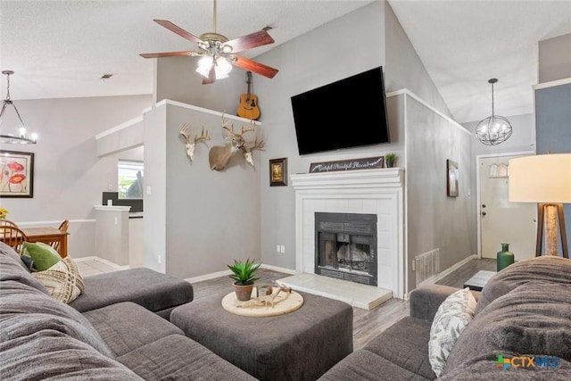 606 Brazos Dr, Temple, TX 76504 - living room with a chandelier, wood finished floors, ceiling fan, a tiled fireplace, and high vaulted ceiling
