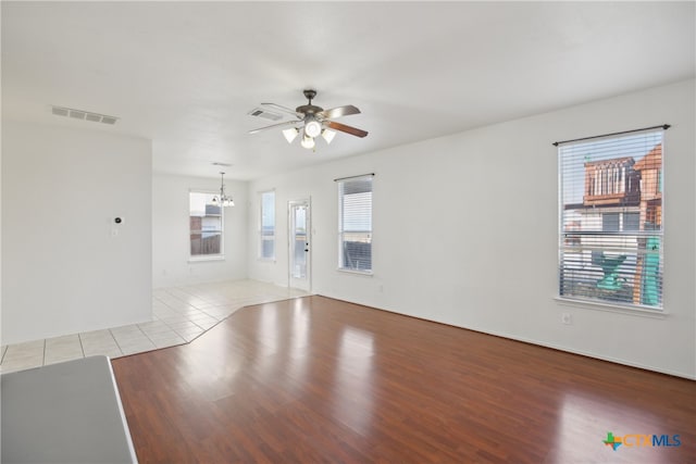 spare room featuring ceiling fan with notable chandelier and light wood-type flooring