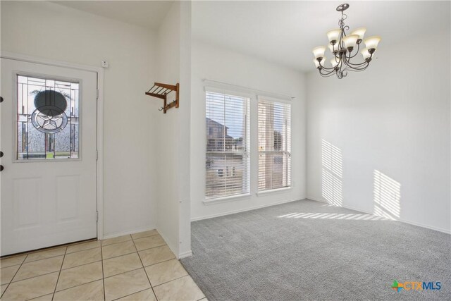 carpeted entryway with a chandelier