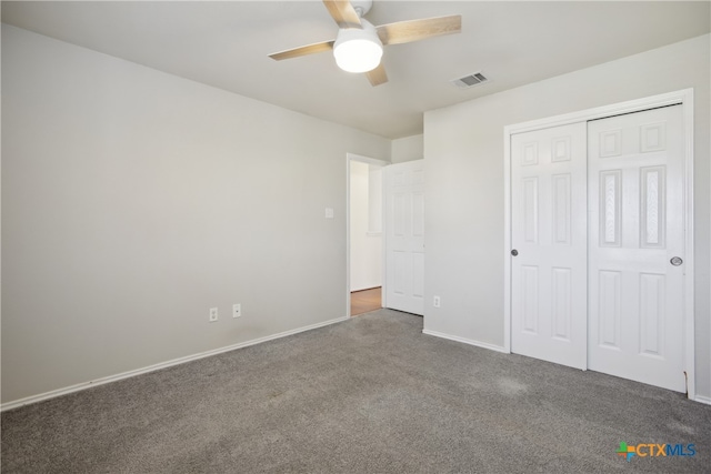 unfurnished bedroom with dark colored carpet, ceiling fan, and a closet