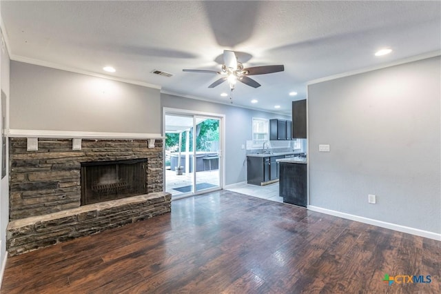 1109 Meadow Dr, Killeen, TX 76549 - unfurnished living room with ceiling fan, wood finished floors, a stone fireplace, crown molding, and baseboards