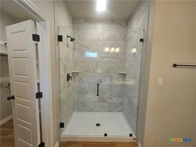 bathroom with a shower stall, baseboards, and wood finish floors