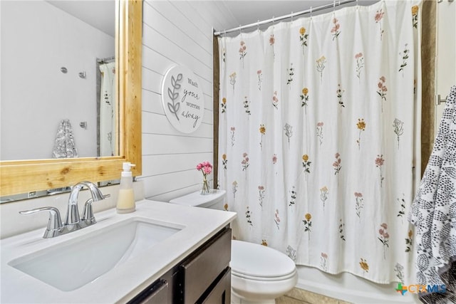 full bath featuring toilet, wood walls, and vanity