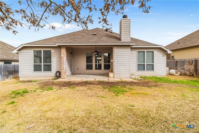 back of property with a ceiling fan, a patio, a fenced backyard, a yard, and a chimney