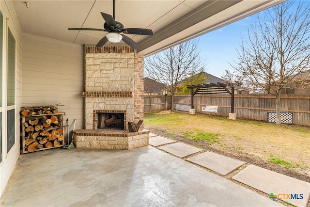 view of patio / terrace featuring ceiling fan, a fenced backyard, and an outdoor stone fireplace