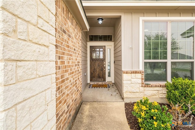 view of exterior entry featuring brick siding, stone siding, and board and batten siding