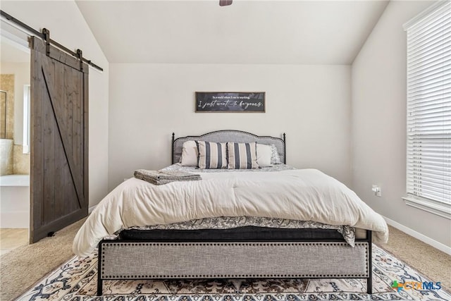 carpeted bedroom with a barn door, baseboards, connected bathroom, and vaulted ceiling