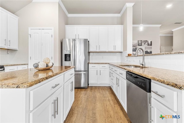 kitchen with light stone countertops, a sink, appliances with stainless steel finishes, crown molding, and light wood-type flooring