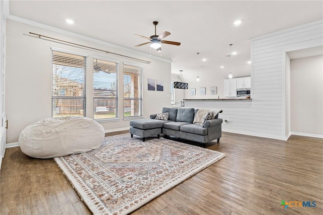 living room featuring ornamental molding, baseboards, and wood finished floors