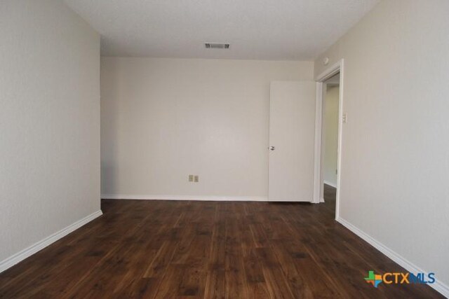 empty room with baseboards, hardwood / wood-style floors, and visible vents