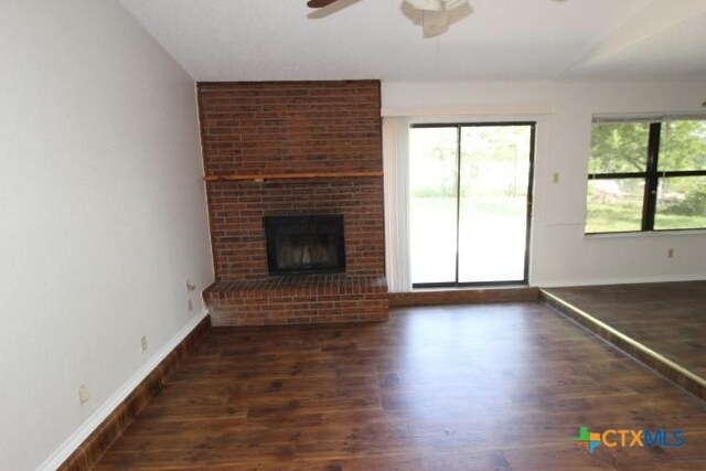 unfurnished living room with baseboards, ceiling fan, a fireplace, and wood finished floors