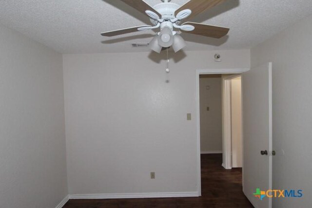 empty room featuring a textured ceiling, baseboards, a ceiling fan, and wood finished floors
