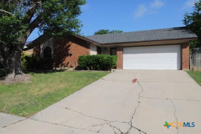 ranch-style home featuring brick siding, a garage, driveway, and a front lawn