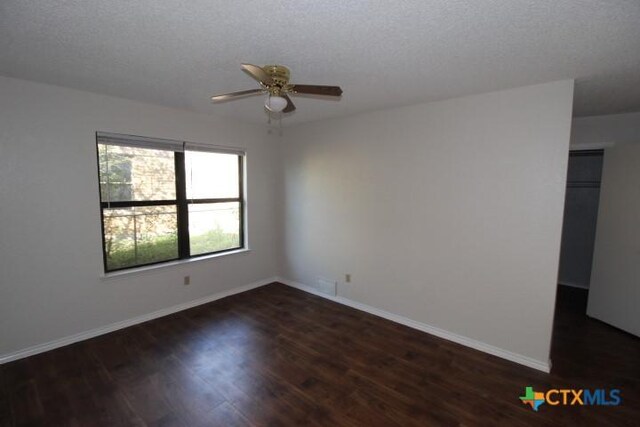 empty room featuring baseboards, dark wood finished floors, and ceiling fan