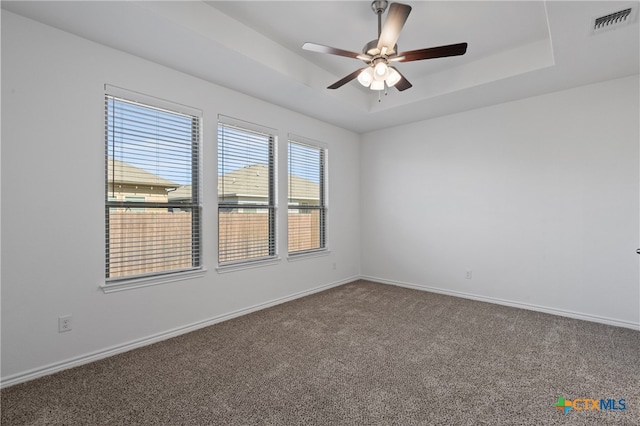 carpeted empty room with a tray ceiling and ceiling fan