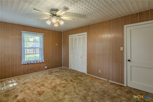 807 E 12th Ave, Belton, TX 76513 - unfurnished bedroom with carpet, a closet, a ceiling fan, and wood walls