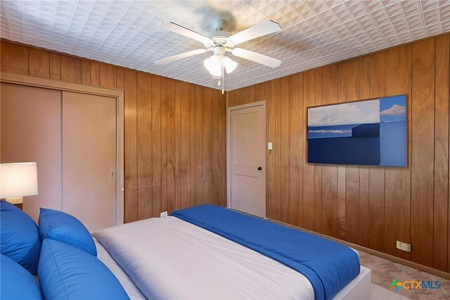 807 E 12th Ave, Belton, TX 76513 - carpeted bedroom featuring a closet, wood walls, and ceiling fan