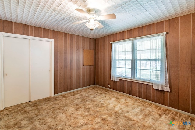 807 E 12th Ave, Belton, TX 76513 - unfurnished bedroom featuring wood walls, carpet floors, a closet, and a ceiling fan