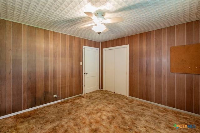 807 E 12th Ave, Belton, TX 76513 - unfurnished bedroom with wood walls, a ceiling fan, and carpet flooring