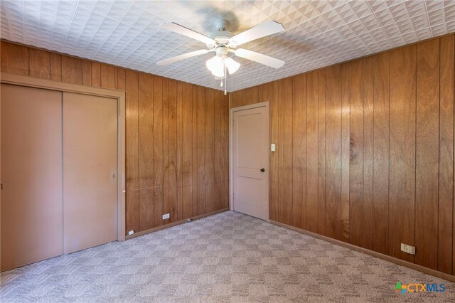 807 E 12th Ave, Belton, TX 76513 - unfurnished bedroom with carpet flooring, a closet, wooden walls, and a ceiling fan