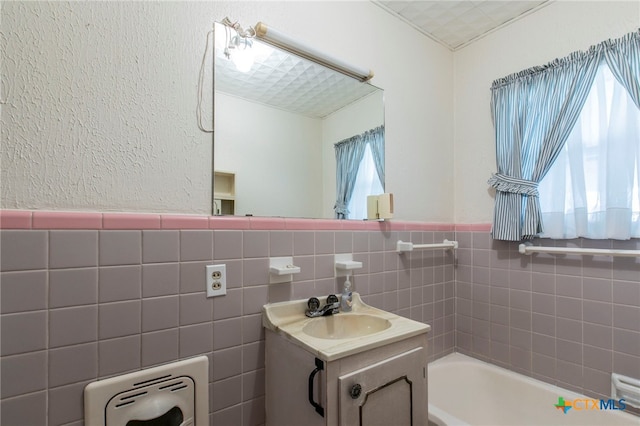 807 E 12th Ave, Belton, TX 76513 - bathroom featuring healthy amount of natural light, vanity, a bathtub, wainscoting, and tile walls