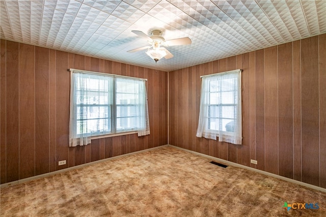 807 E 12th Ave, Belton, TX 76513 - unfurnished room featuring healthy amount of natural light, ceiling fan, wood walls, and carpet floors