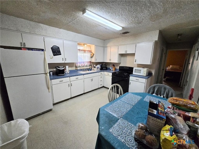 kitchen with light floors, visible vents, white appliances, dark countertops, and white cabinets
